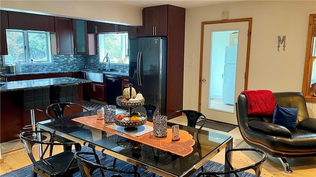 kitchen with light wood-type flooring, tasteful backsplash, plenty of natural light, and black appliances