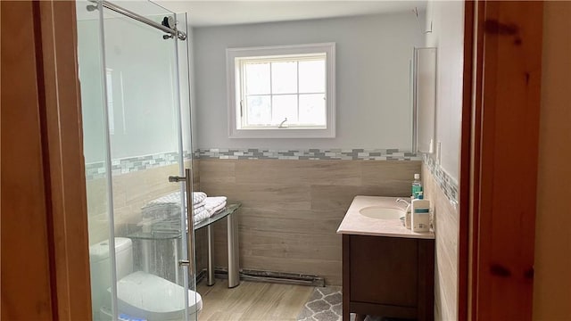 bathroom featuring vanity, toilet, tile walls, and a shower with shower door