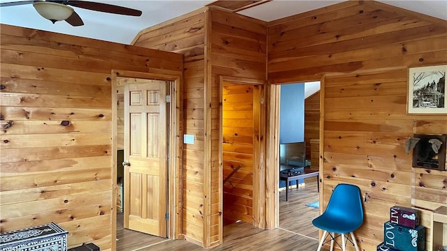 interior space with wood walls, ceiling fan, and hardwood / wood-style flooring