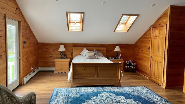 bedroom featuring access to exterior, vaulted ceiling with skylight, baseboard heating, light hardwood / wood-style floors, and wood walls