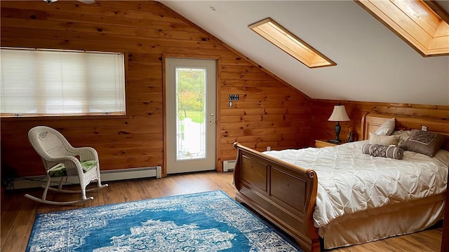 bedroom featuring access to exterior, baseboard heating, wooden walls, vaulted ceiling with skylight, and light wood-type flooring