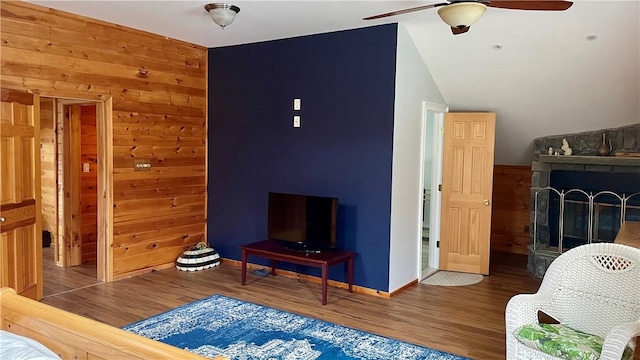 interior space with a fireplace, wood walls, hardwood / wood-style floors, and ceiling fan