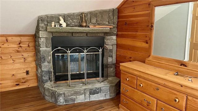 room details with wood-type flooring, a stone fireplace, and wooden walls