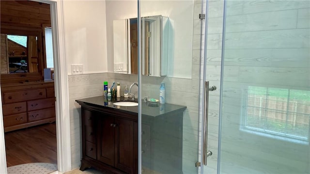 bathroom with hardwood / wood-style floors, vanity, a wealth of natural light, and walk in shower