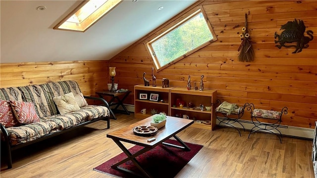 sitting room with hardwood / wood-style flooring, baseboard heating, wood walls, and vaulted ceiling with skylight