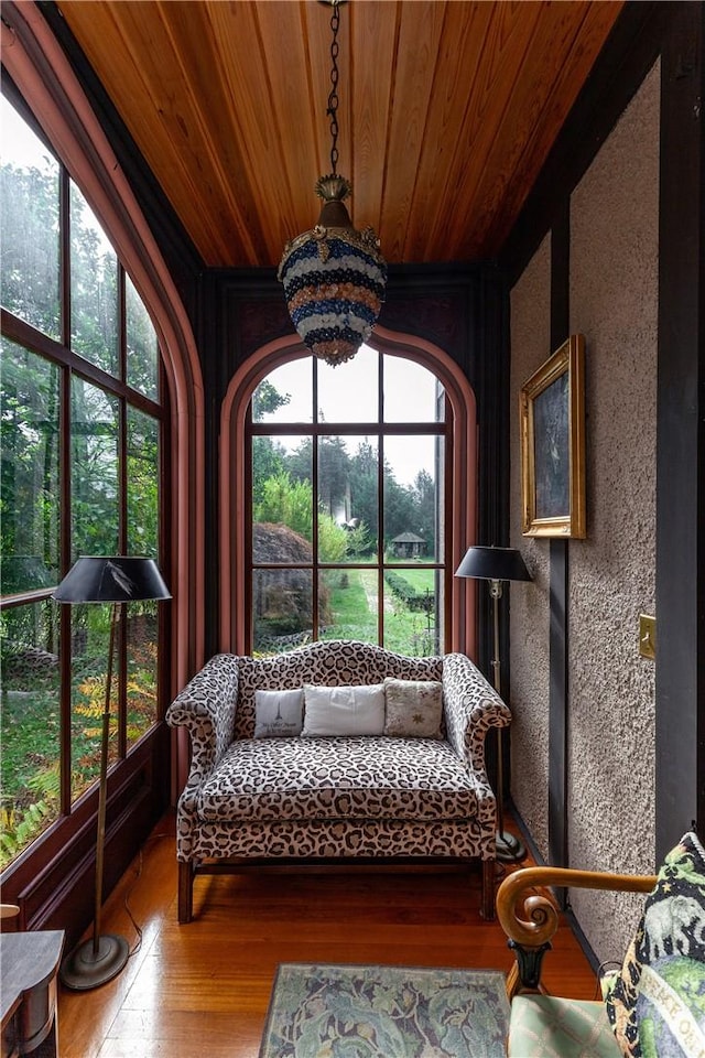 sunroom with a notable chandelier, a healthy amount of sunlight, and wood ceiling