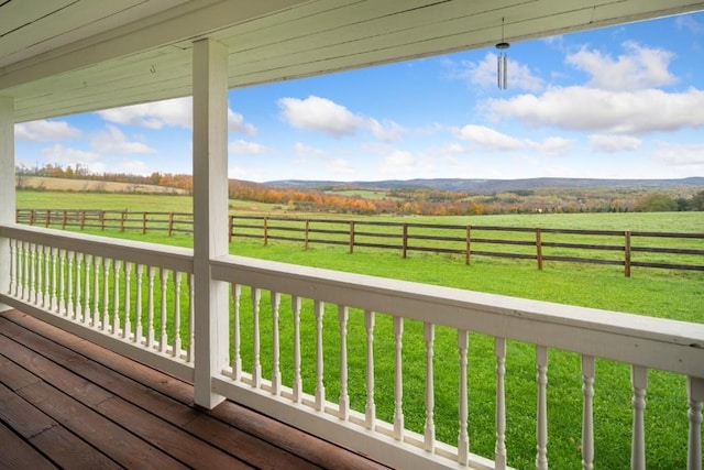 wooden terrace with a yard and a rural view