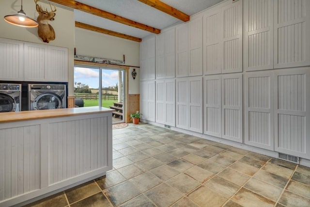 kitchen featuring beam ceiling, white cabinetry, hanging light fixtures, and washing machine and clothes dryer