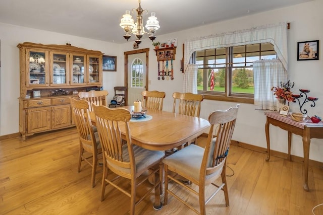 dining room featuring a healthy amount of sunlight, light hardwood / wood-style floors, and an inviting chandelier