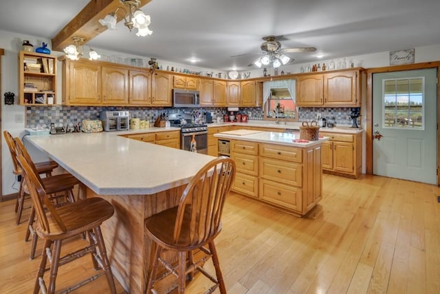 kitchen with a kitchen bar, appliances with stainless steel finishes, decorative backsplash, beam ceiling, and light hardwood / wood-style floors