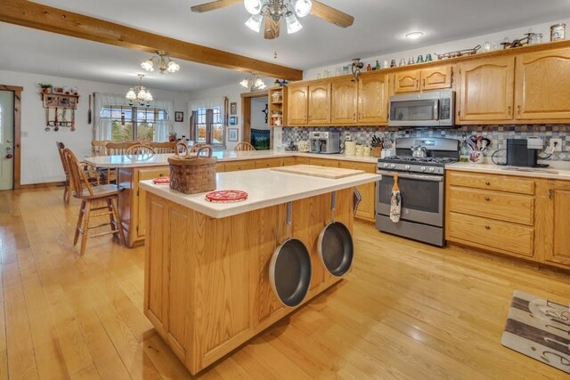 kitchen featuring beam ceiling, light hardwood / wood-style floors, a breakfast bar area, a kitchen island, and appliances with stainless steel finishes