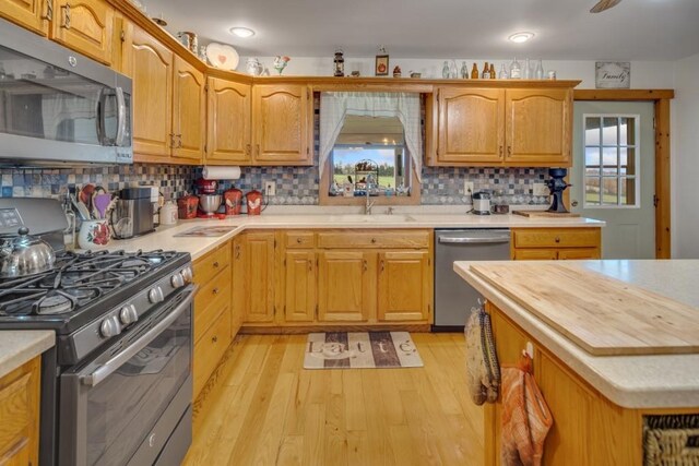 kitchen featuring decorative backsplash, sink, light hardwood / wood-style floors, and appliances with stainless steel finishes