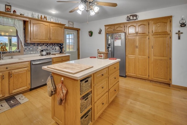 kitchen with sink, tasteful backsplash, appliances with stainless steel finishes, a kitchen island, and light wood-type flooring