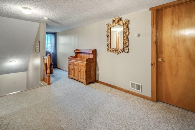 interior space featuring lofted ceiling, light carpet, and a textured ceiling