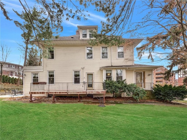 rear view of house featuring a lawn and a deck