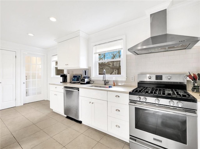 kitchen featuring backsplash, wall chimney exhaust hood, stainless steel appliances, sink, and white cabinetry