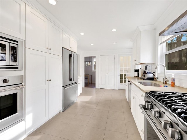 kitchen with white cabinetry, sink, stainless steel appliances, light tile patterned flooring, and ornamental molding