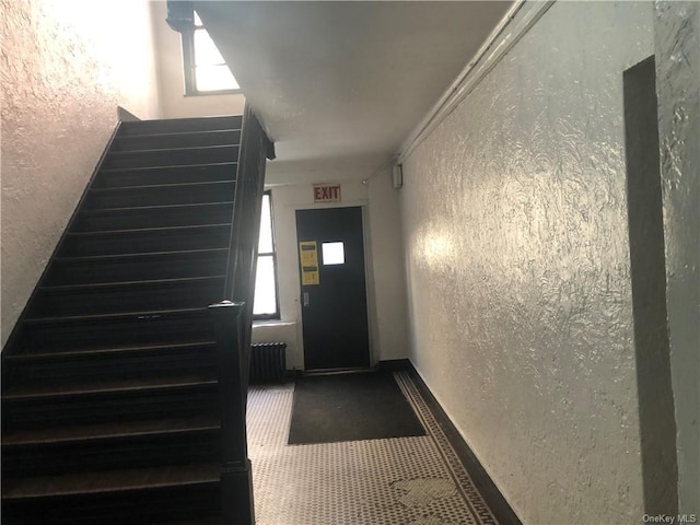 stairs featuring crown molding and radiator heating unit