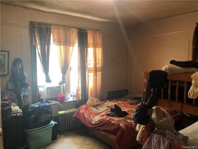 bedroom featuring cooling unit, a textured ceiling, and radiator