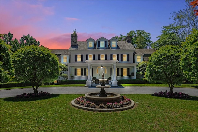 colonial inspired home with a lawn and a porch