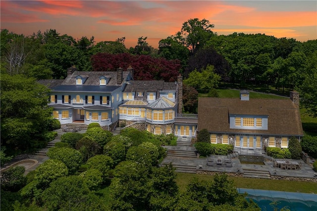 back house at dusk featuring a patio