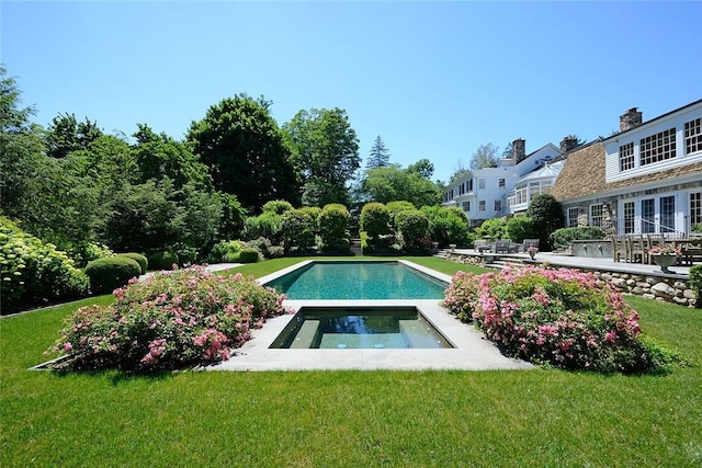 view of swimming pool featuring a lawn and an in ground hot tub