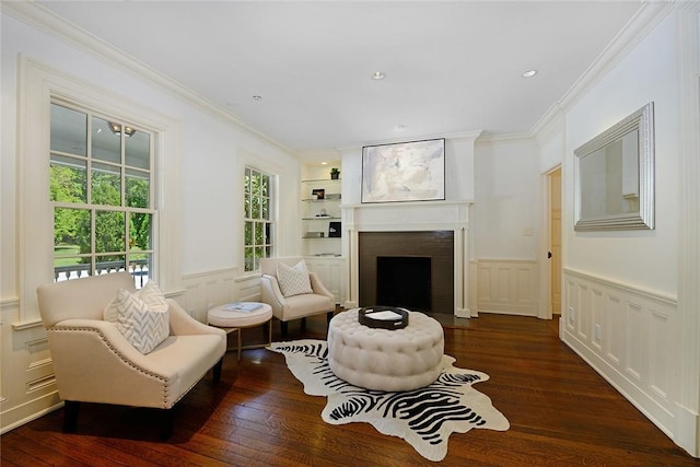 sitting room featuring ornamental molding, built in shelves, and dark wood-type flooring