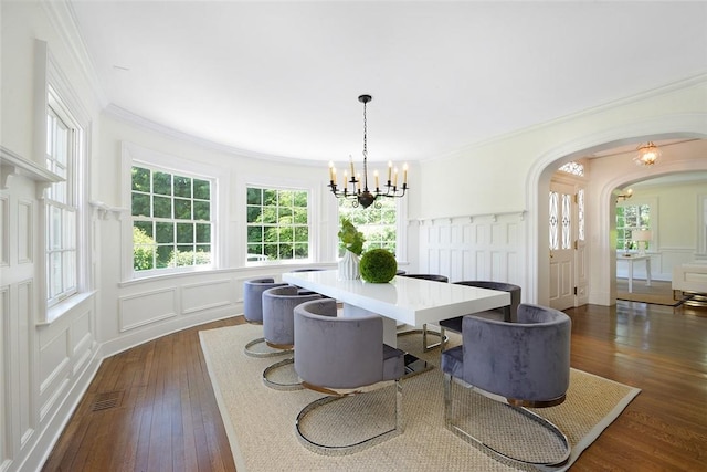 dining area featuring a notable chandelier, dark hardwood / wood-style floors, ornamental molding, and a wealth of natural light