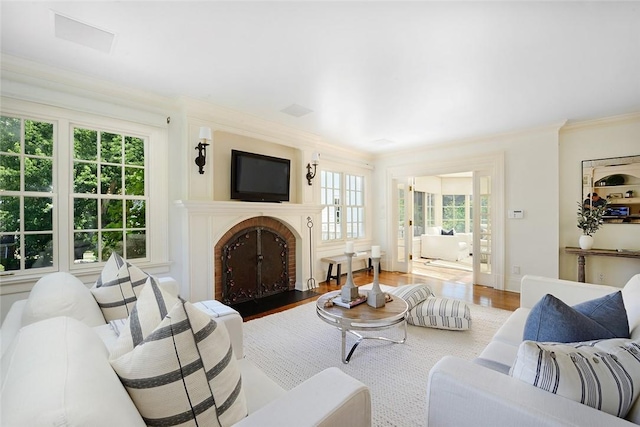 living room with a wealth of natural light, wood-type flooring, and ornamental molding