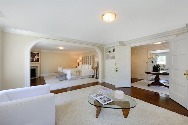 living room with ornamental molding, dark wood-type flooring, and a brick fireplace