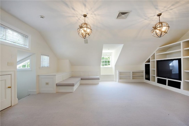 additional living space with an inviting chandelier, light carpet, a wealth of natural light, and vaulted ceiling