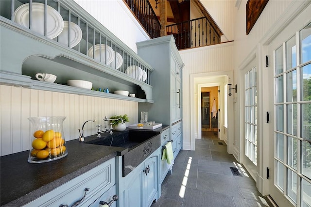 kitchen with white cabinets, a towering ceiling, and sink