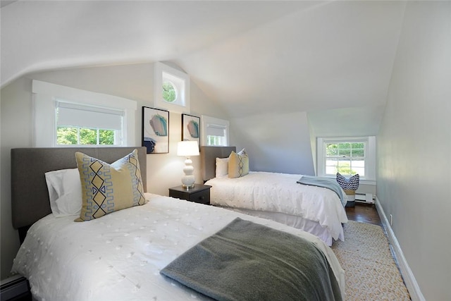 bedroom featuring hardwood / wood-style floors, vaulted ceiling, and a baseboard heating unit