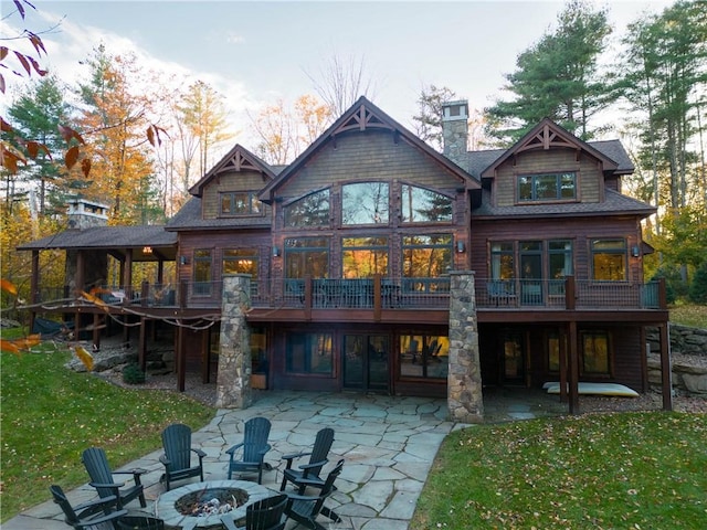 back of property featuring a patio, a fire pit, a wooden deck, and a lawn