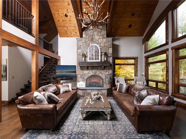 living room with dark hardwood / wood-style flooring, wood ceiling, an inviting chandelier, high vaulted ceiling, and a stone fireplace