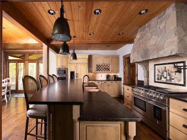 kitchen featuring sink, dark hardwood / wood-style floors, an island with sink, appliances with stainless steel finishes, and beam ceiling