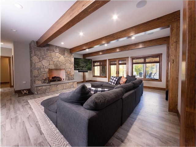 living room featuring beam ceiling, a stone fireplace, light hardwood / wood-style flooring, and french doors