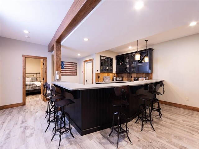 bar with decorative light fixtures and light hardwood / wood-style floors