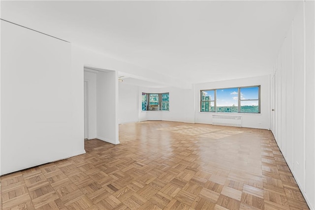 unfurnished living room featuring radiator heating unit and light parquet floors