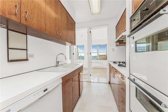 kitchen with radiator heating unit, white appliances, and sink