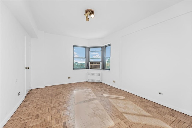 spare room with radiator heating unit and light parquet floors