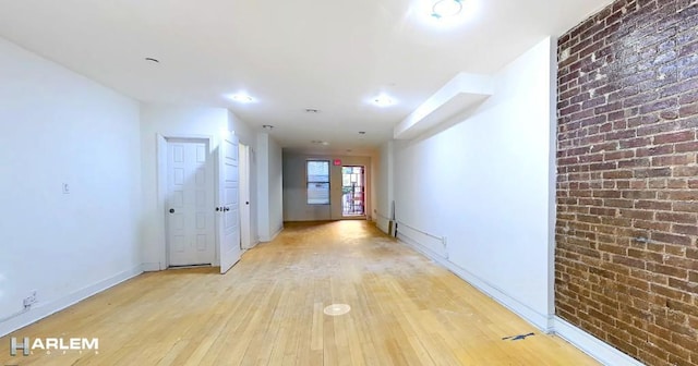 hall featuring light hardwood / wood-style floors and brick wall