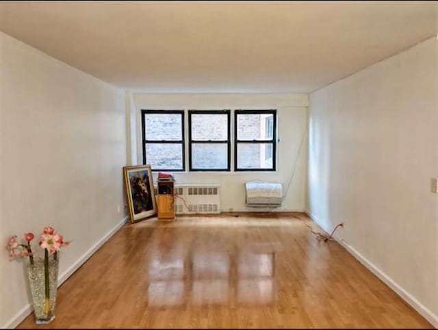 unfurnished room with hardwood / wood-style flooring and radiator