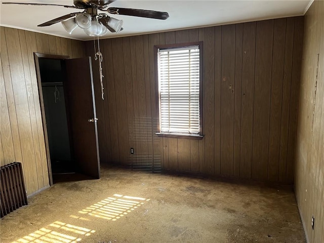 unfurnished room featuring ceiling fan and wood walls