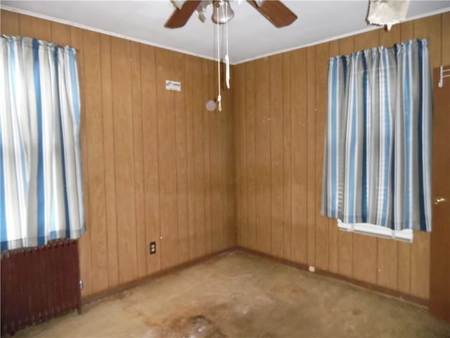 unfurnished room featuring wooden walls, radiator heating unit, and ceiling fan