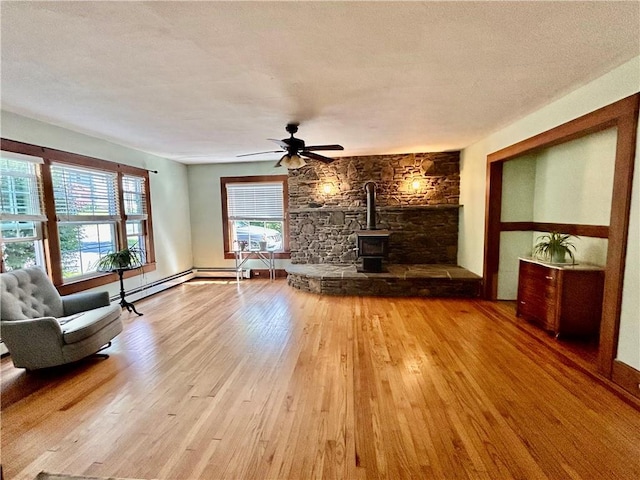 unfurnished living room featuring a wood stove, ceiling fan, hardwood / wood-style floors, and a textured ceiling