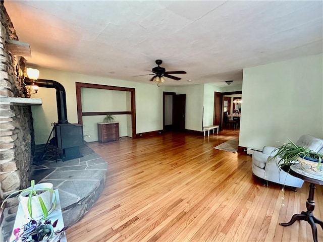 living room with hardwood / wood-style floors, a wood stove, and ceiling fan