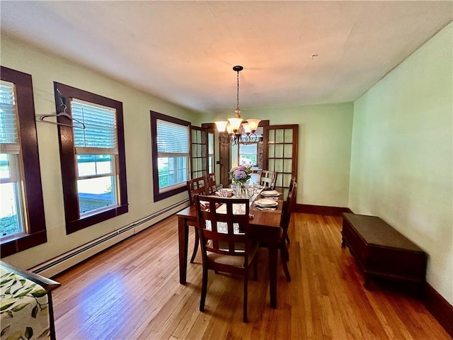 dining room featuring hardwood / wood-style floors, baseboard heating, and a chandelier