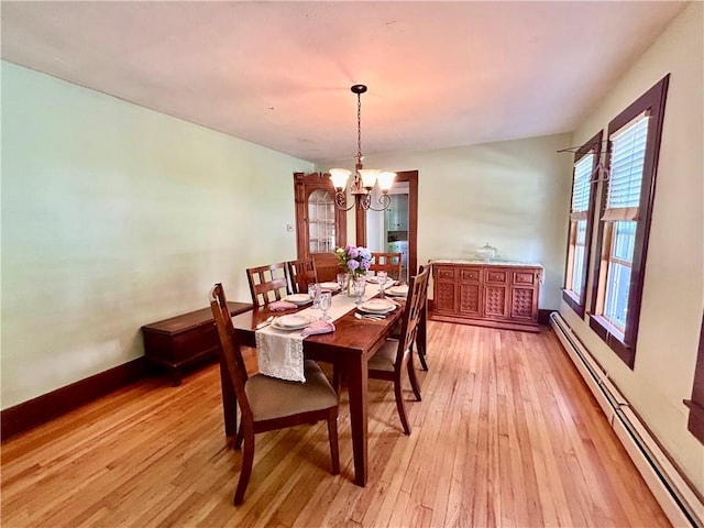 dining room featuring light hardwood / wood-style flooring, a chandelier, and a baseboard heating unit