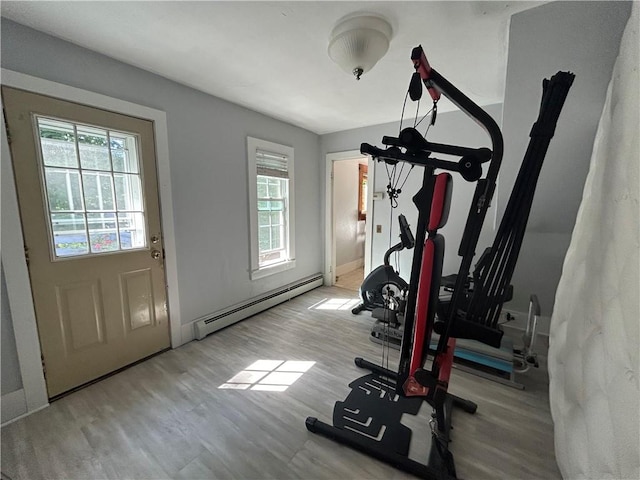 exercise room with a wealth of natural light, light wood-type flooring, and baseboard heating